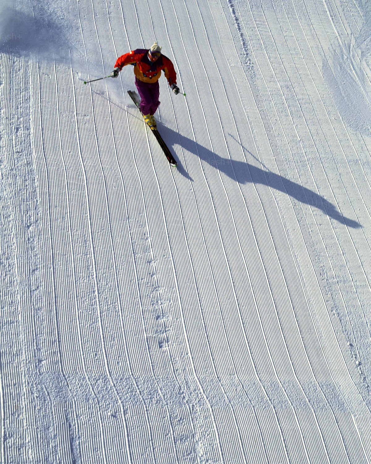 Skier carving down a groomed slope